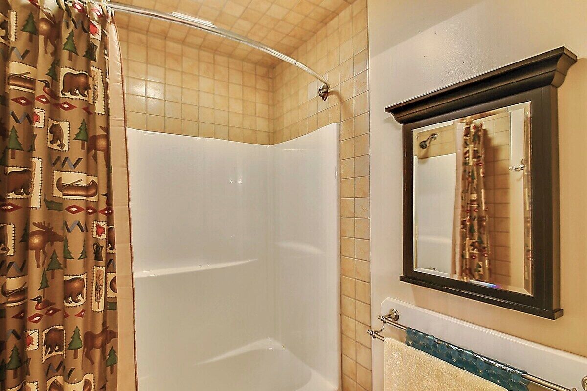 A bathroom with a shower, a towel rack, and a mirror.