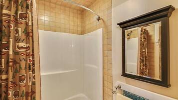A bathroom with a shower, a towel rack, and a mirror.