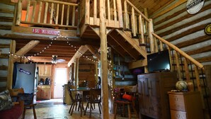A wooden cabin interior with a dining area, kitchen, and a sign indicating a ski instructor.