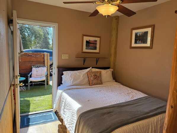 A bedroom with a bed, a ceiling fan, and two framed pictures on the wall.