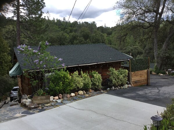 A wooden cabin with a stone foundation, surrounded by a stone wall and a wooden fence.