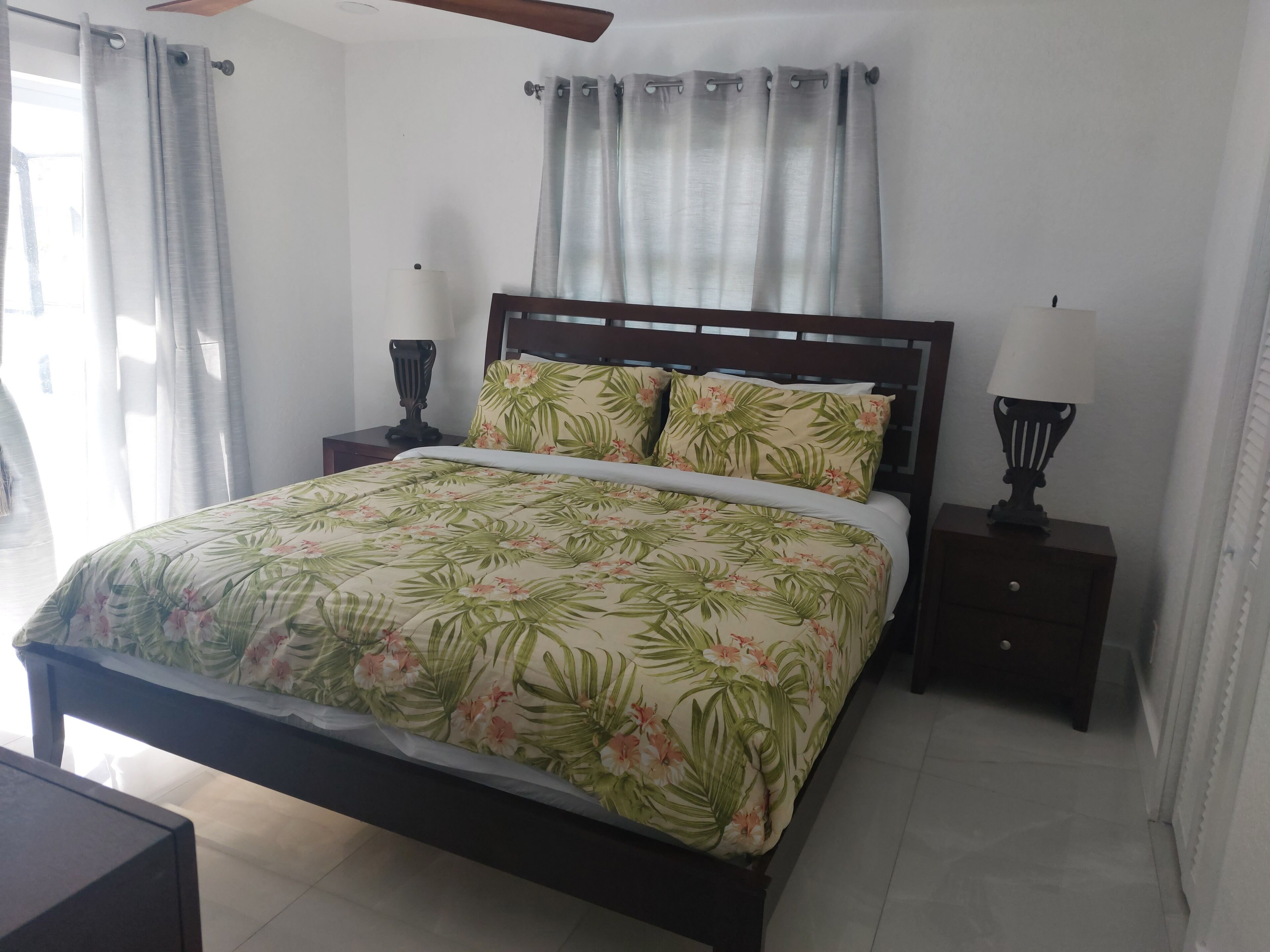 A bedroom with a bed, two bedside tables, and a ceiling fan.