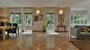Amplia sala de estar con comedor, ventanas grandes y un sofá gris.