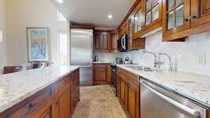 Una cocina con armarios de madera, encimeras de granito, electrodomésticos de acero inoxidable y salpicadero de azulejos.