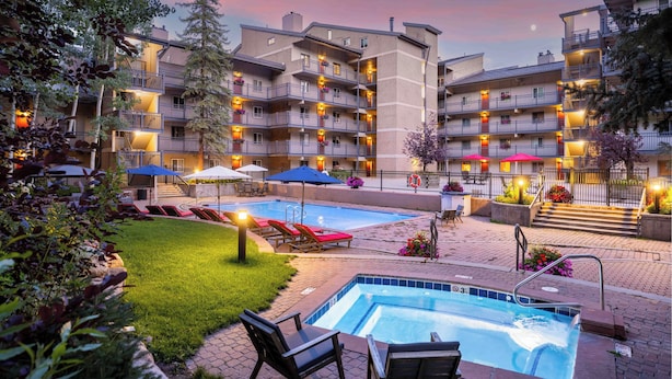 Un hotel con varios balcones, piscina y zonas de estar al aire libre.