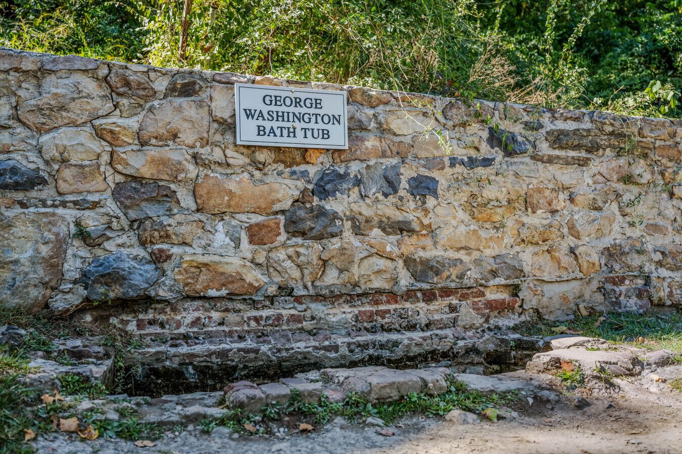 A stone wall with a sign reading "GEORGE WASHINGTON BATH TUB".