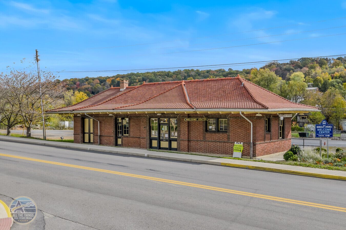 A brick building with a red-tiled roof, labeled as a 'Welcome Center' with a sign indicating parking.