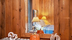 A wooden room with a bed, a lamp, and a decorative item on a checkered tablecloth. - Haven Home - deck, grill, wifi, pool access, hiking, wood stove, games (Berkeley Springs)
