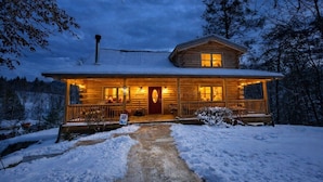 A log cabin with a front porch, a chimney, and a snow-covered landscape. - Bison Overlook Lodge: on a 65-acre bison ranch (Clyde)