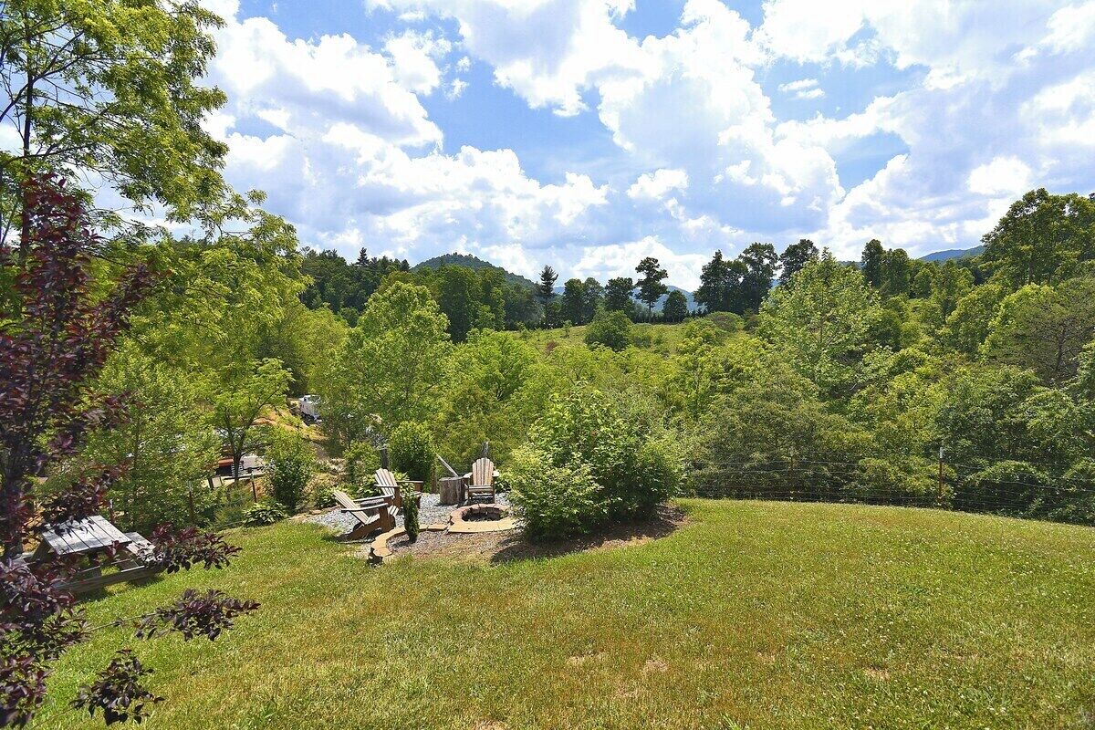 A lush green landscape with a small outdoor seating area and a fire pit.