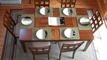 Una mesa de madera para comer con seis sillas, cada una con un mantel individual reflectante.