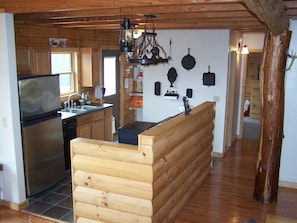 A kitchen with a wooden bench, stainless steel appliances, and wall-mounted cookware.