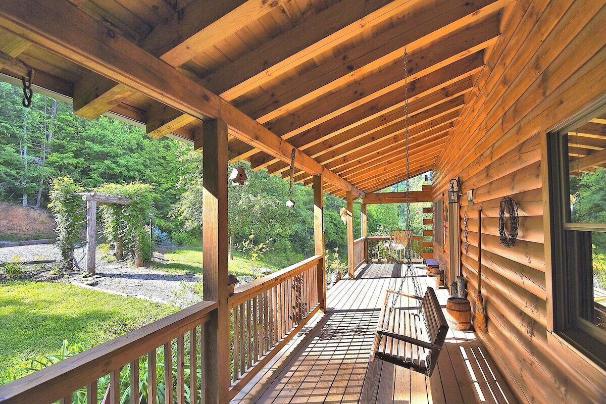 A wooden deck with a railing, a bench, and a hanging light fixture.