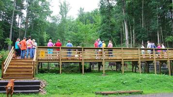 A group of people on a wooden bridge in a wooded area.