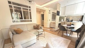 A modern living room with a sofa, a coffee table, and a dining area with chairs and a table.
