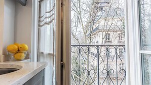 A kitchen with a bowl of lemons on the counter, a window with a view of a building and trees.
