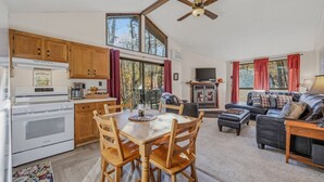 Une cuisine spacieuse avec des meubles en bois, une table à manger avec des chaises, une cheminée et un coin salon avec un canapé et un téléviseur.