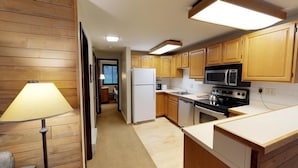 A compact kitchen with wooden cabinets, a refrigerator, a microwave, a stove, and a sink. - Terracehouse - Steps to Slopes - Hot Tub/Pool - ASE Transportation (Snowmass Village)
