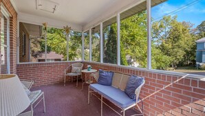 Un patio couvert avec un mur en briques, un canapé, une chaise et une petite table.