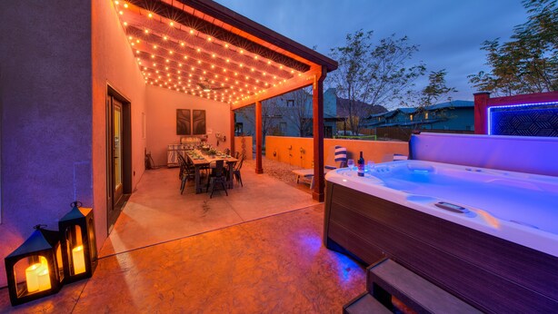 An outdoor patio with a dining table, chairs, and a hot tub. - SG3 Private hot tub, Ping pong, Badminton, Huge Patio, Views (Moab)