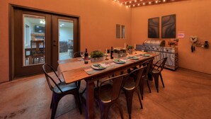 A dining area with a wooden table set for six, surrounded by chairs. There is a grill and decorative lights on the ceiling. - SG3 Private hot tub, Ping pong, Badminton, Huge Patio, Views (Moab)