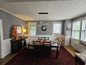 A dining area with a table set for four, a black cabinet, and a radiator.