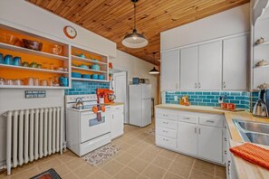 Una cocina con armarios blancos, una estufa y un reloj en la pared.