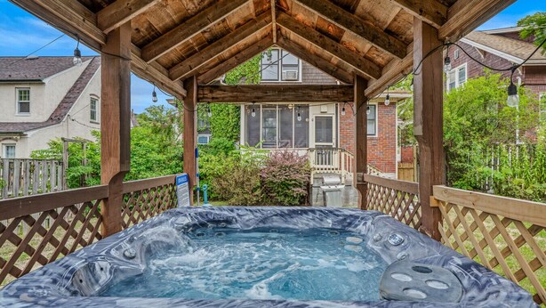 Un bain à remous sous une pergola en bois, avec vue sur les maisons au loin.