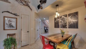 A dining area with a wooden table, colorful chairs, and artwork on the walls. - DW6  Private Hot Tub, En-Suite Bathroom for Each Bedroom, Near Arches Park! (Moab)
