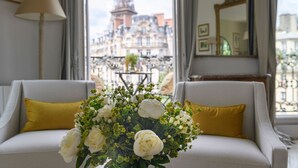 A room with a view of the Eiffel Tower, featuring a sofa with yellow cushions, a vase of white flowers, and a lamp. - Amazing Balcony and Pinch-Yourself Eiffel Views! (Paris)
