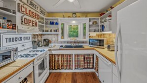 Una cocina con una isla central, armarios blancos, estufa, microondas y refrigerador.