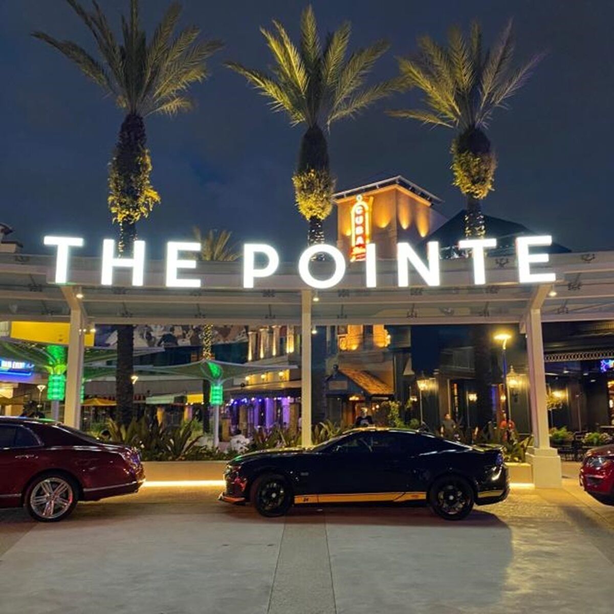 A hotel entrance with a sign reading "THE POINTE" and two cars parked in front.