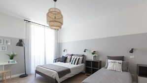 A modern bedroom with two beds, a desk, a chair, and a floor lamp. - Pannonia Smart House (Rome)