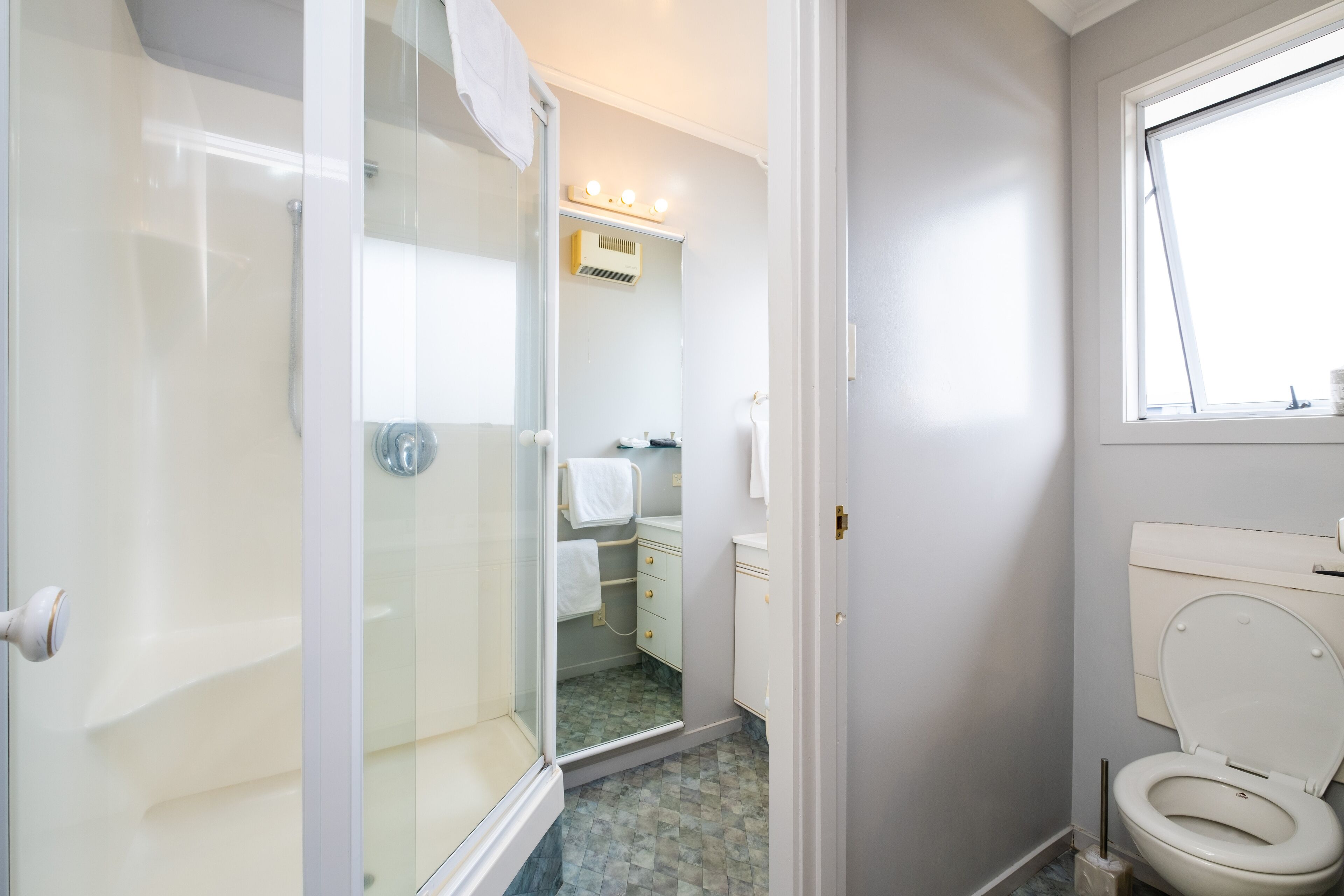 A bathroom with a glass shower enclosure, a toilet, and a sink.