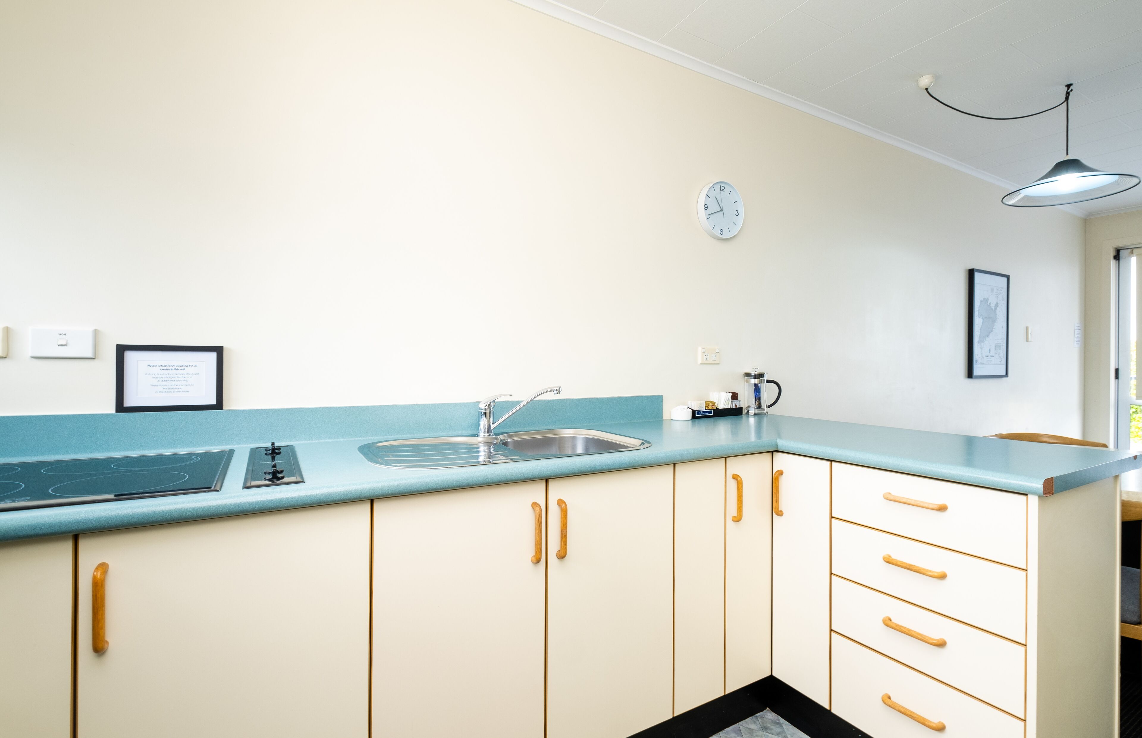 A kitchen with a light blue countertop, a stainless steel sink, and wooden cabinets.