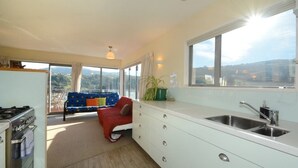 A modern kitchen with a large window, a sofa, and a view of the outdoors. - Baldwin Street BNB (Dunedin)