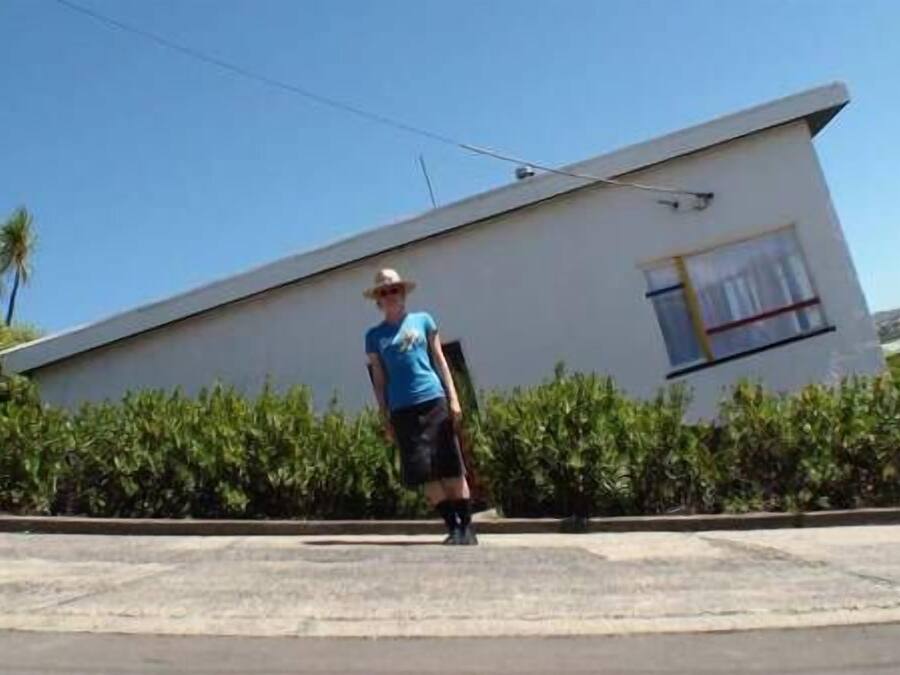 Una persona de pie sobre una superficie de hormigón con un edificio al fondo.