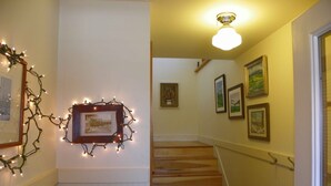 A staircase with wooden steps and a handrail, leading to a room with a ceiling light fixture.