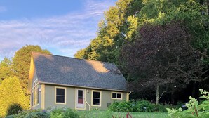 A house with a sloped roof, surrounded by a garden with various plants and flowers.