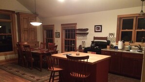 A kitchen with wooden cabinets, a dining table with chairs, a bar area, and a stove.