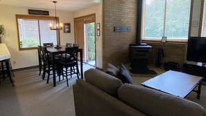 Una sala de estar con sofá, mesa de comedor con sillas, chimenea y televisor.
