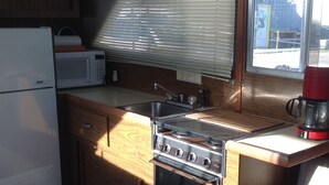 A compact kitchen with wooden cabinets, a white refrigerator, a stove, and a microwave. - A vacation you won't forget, stay on a 35 foot boat! (Bayfield)