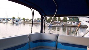 A boat interior with blue and white seating, a canopy, and a view of a marina with boats and buildings. - A vacation you won't forget, stay on a 35 foot boat! (Bayfield)