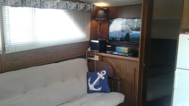 A compact RV interior with a sofa, a television, and a small kitchen area. - A vacation you won't forget, stay on a 35 foot boat! (Bayfield)