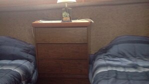 A small, dimly lit room with two beds, a wooden nightstand, and a lamp. - A vacation you won't forget, stay on a 35 foot boat! (Bayfield)