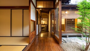 Un intérieur japonais traditionnel, avec un plancher en bois, des portes coulissantes et une vue sur l’extérieur.