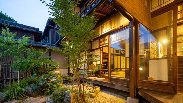 Un bâtiment de style japonais traditionnel, doté d’un jardin agrémenté de rochers, d’un petit arbre et d’un bassin à carpes koï.