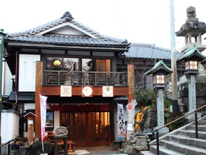 A traditional Japanese building with a wooden facade, a tiled roof, and a stone lantern.