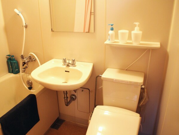 A bathroom with a sink, toilet, and shower. There are toiletries on a shelf.