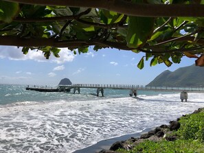 A pier extending into the ocean with a mountainous backdrop.